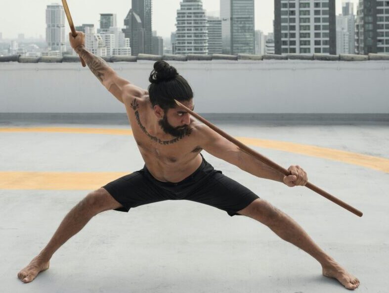 Martial artist practicing on a rooftop, against a city skyline backdrop.